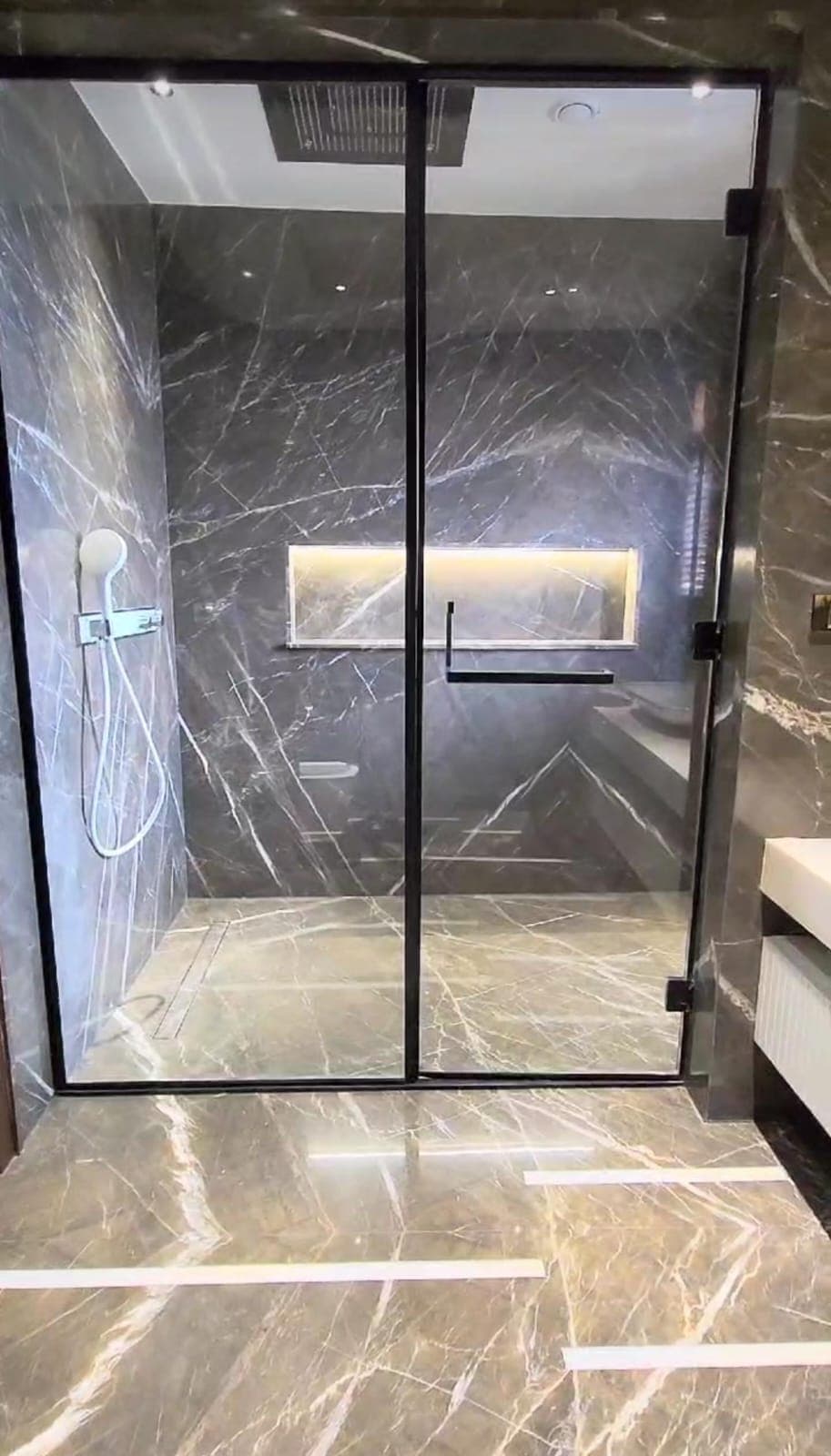 Fixed frameless glass panel beside a walk-in shower
